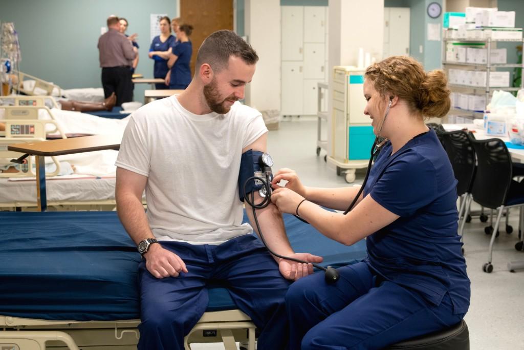 A nursing student takes another student's blood pressure in UNE's Interprofessional Simulation and Innovation Center