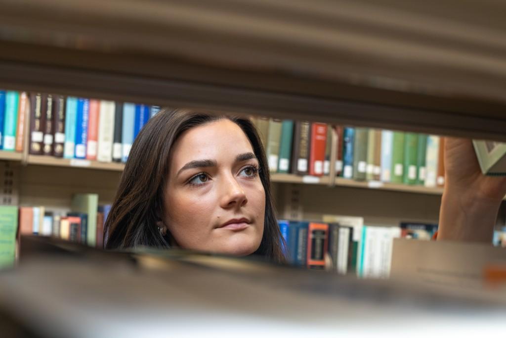 A u n e student searches a bookshelf