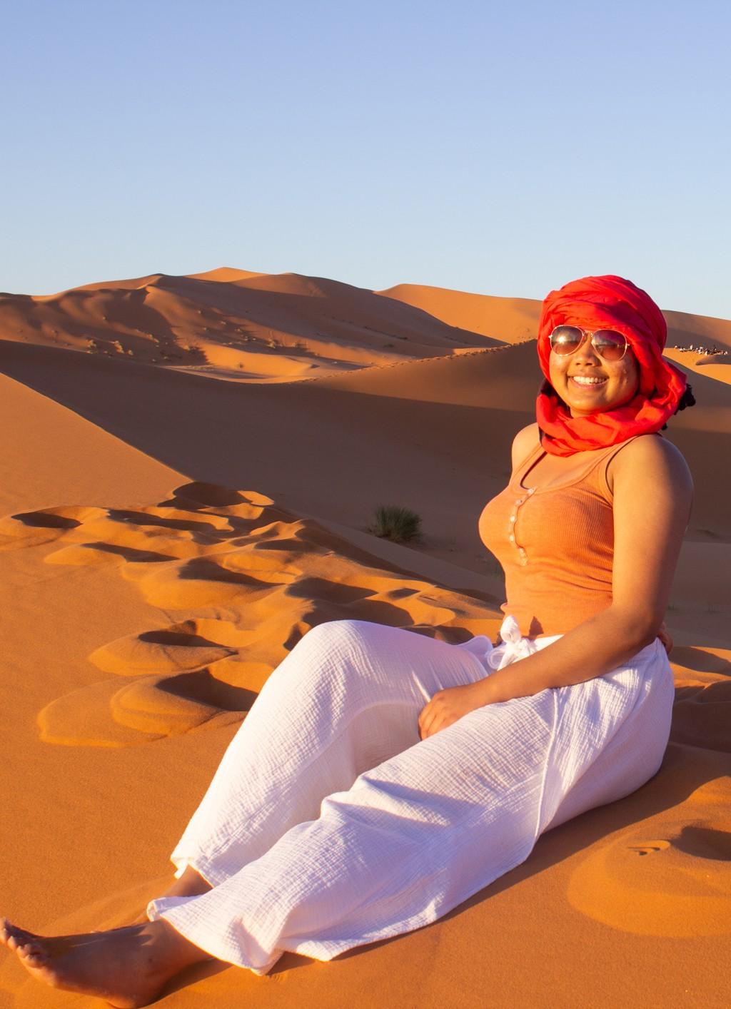 一个学生坐在摩洛哥沙漠的沙滩上