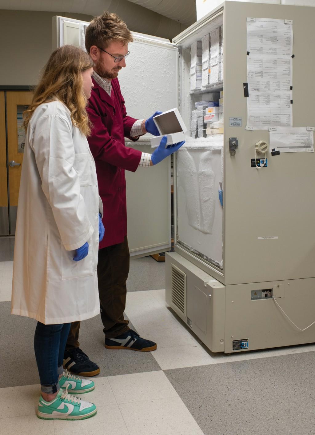 Jayden and Dr. Harrison stand in front of an open lab freezer