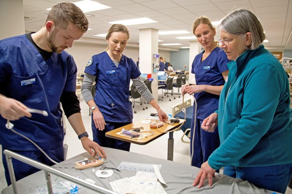 A nursing professor explains hospital tools to three students